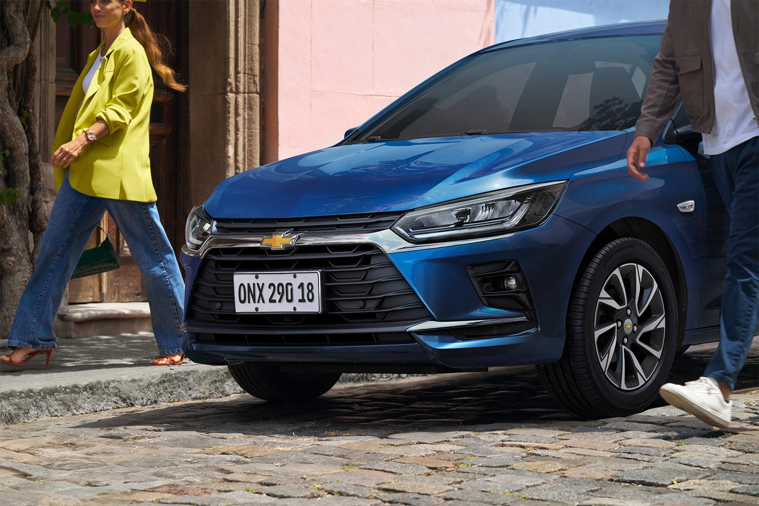 Chevrolet Onix Hatchback azul visto desde el frente con personas caminando