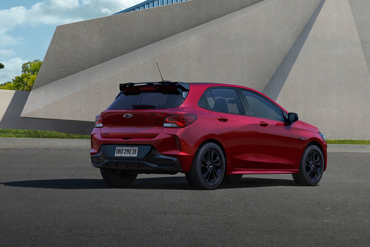 Automóvil Chevrolet rojo estacionado frente a una estructura arquitectónica moderna.