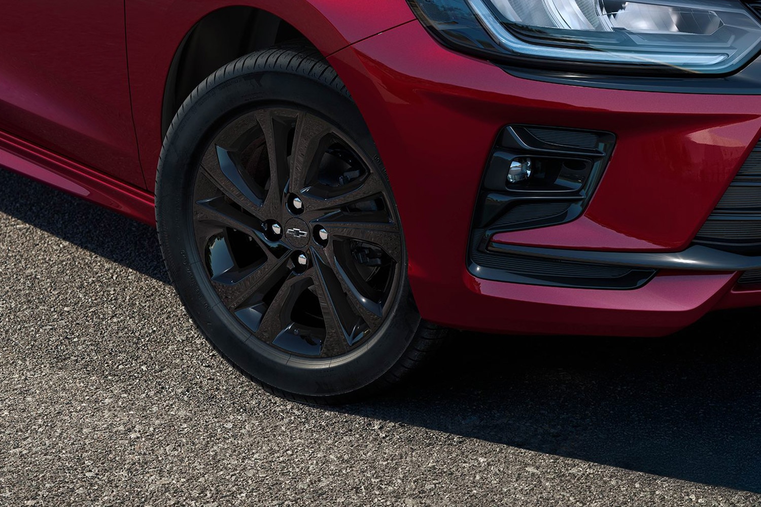 Detalle del rin delantero de un automóvil Chevrolet rojo sobre asfalto